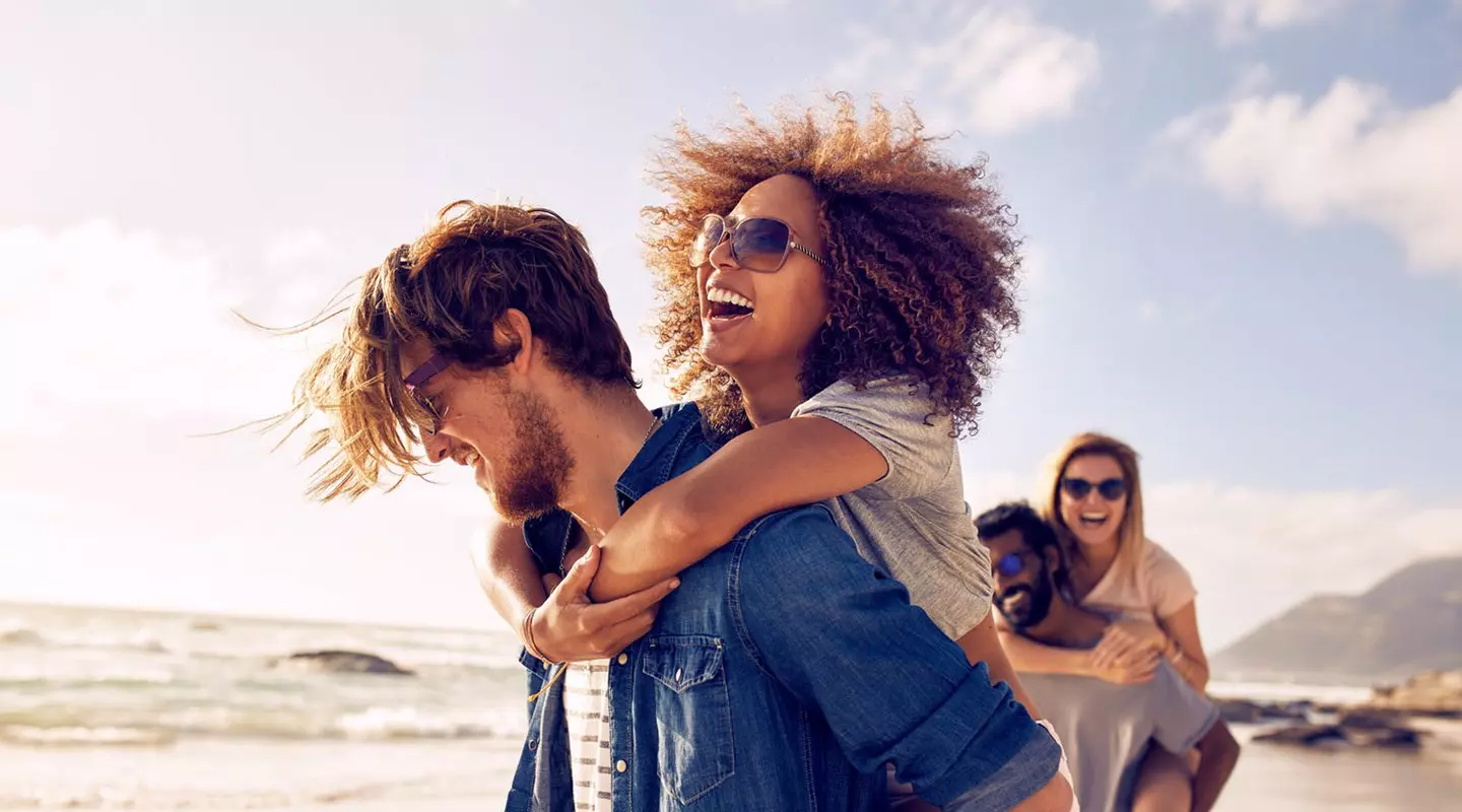 Couple piggyback ride on the beach