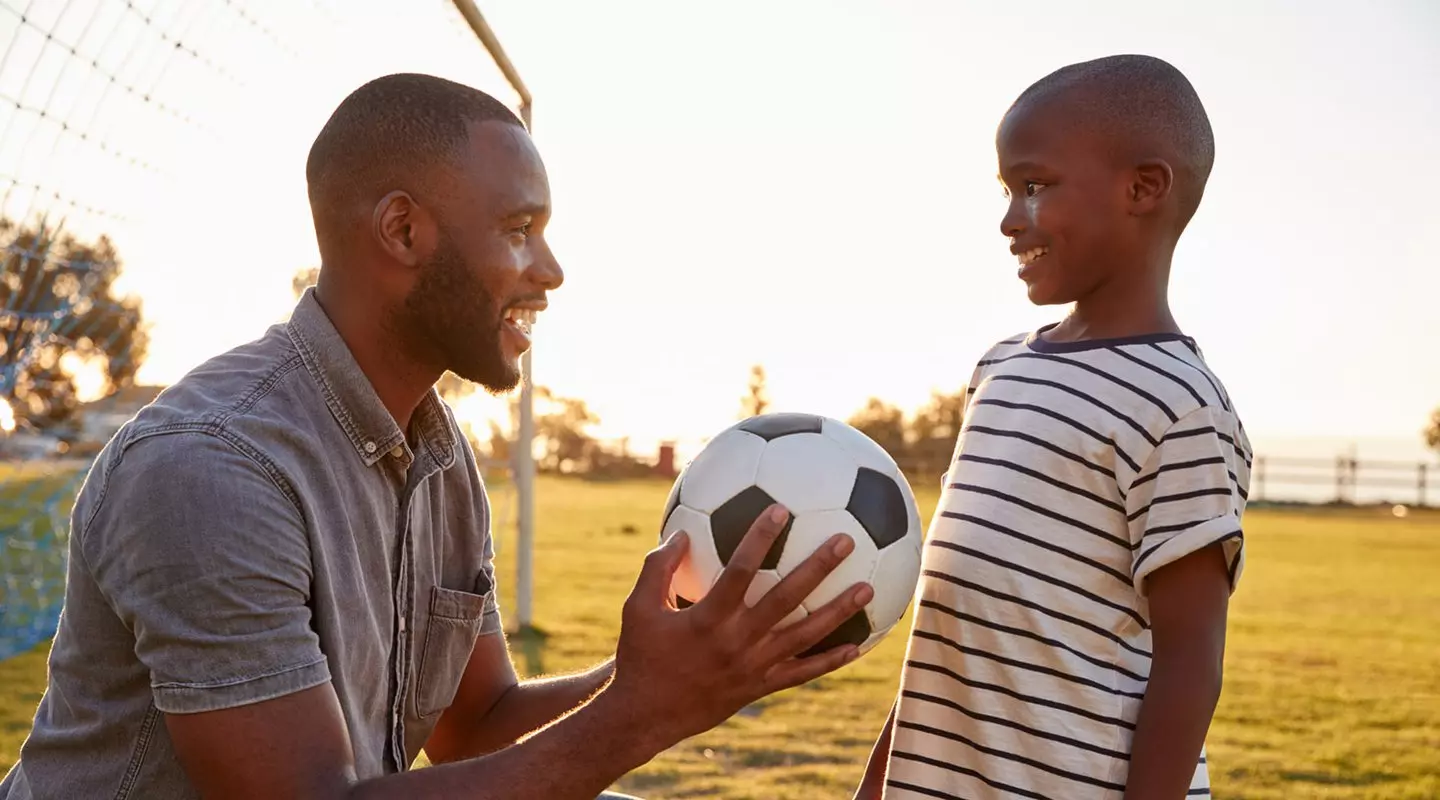 Black father and son playing soccer