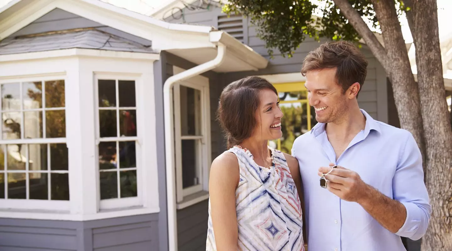 Couple holding keys in front of house