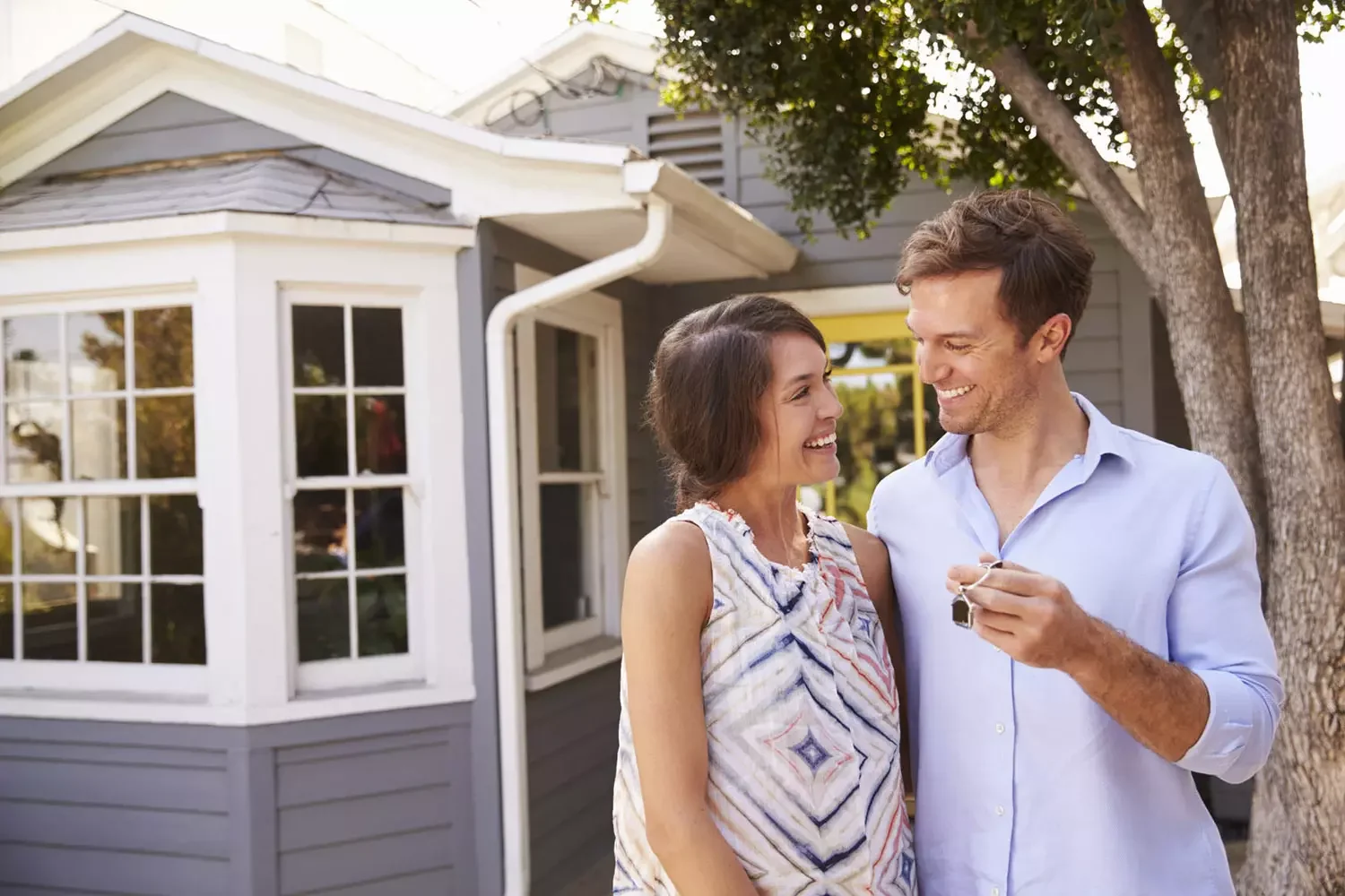 Couple holding keys in front of house