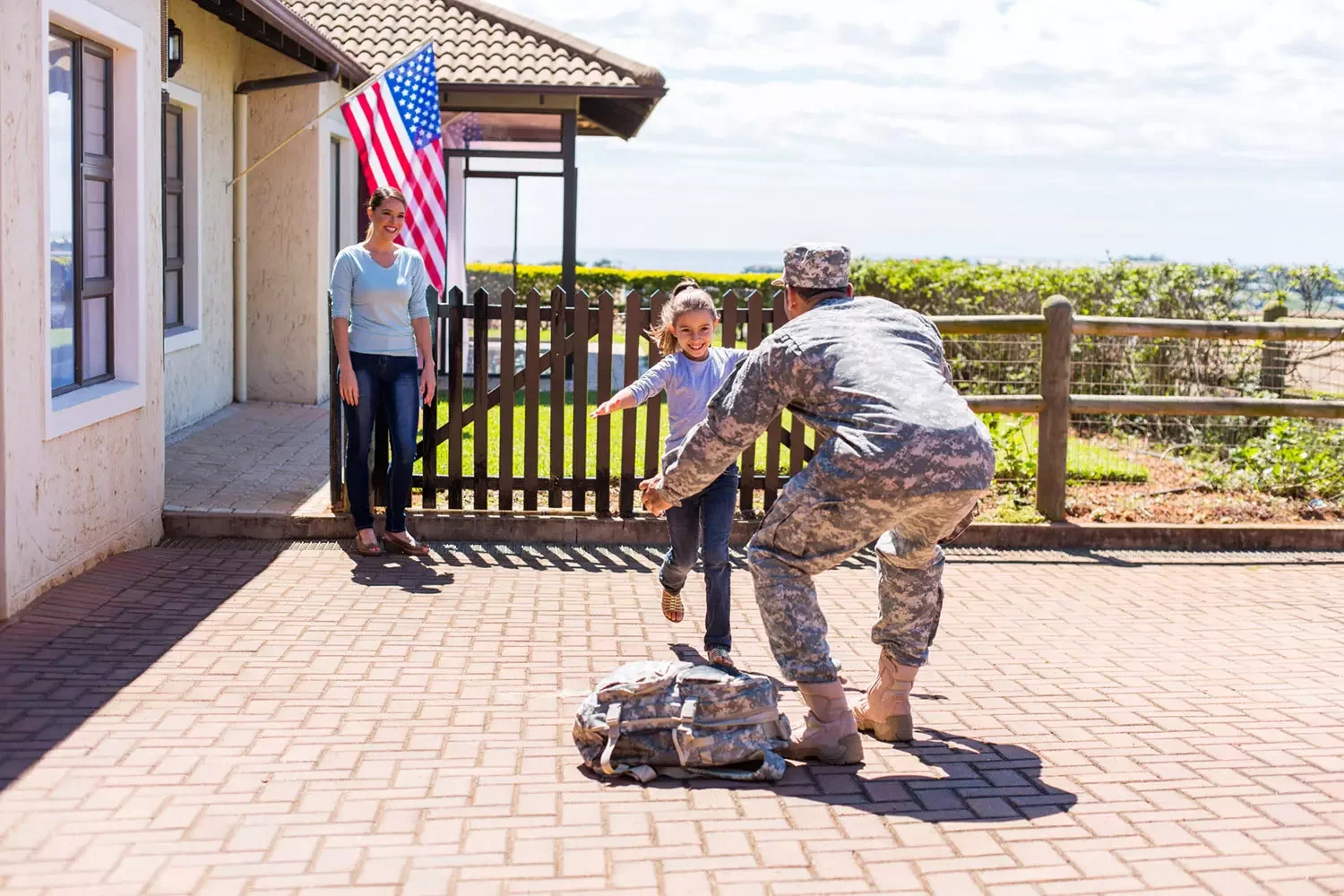 Soldier hugging daughter in front of house