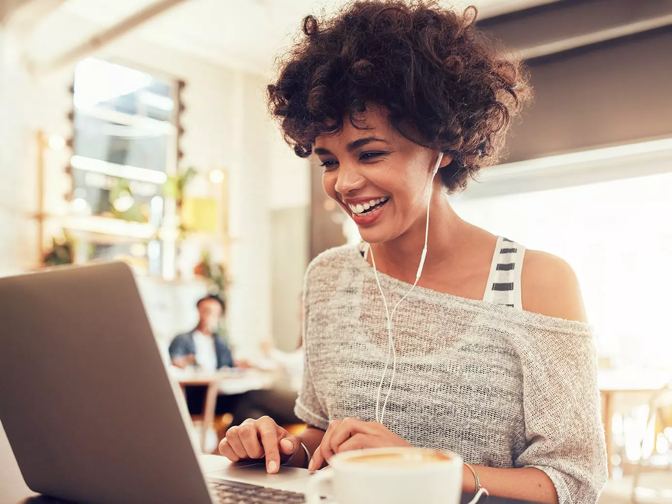 Black woman smiling listening to music on her laptop