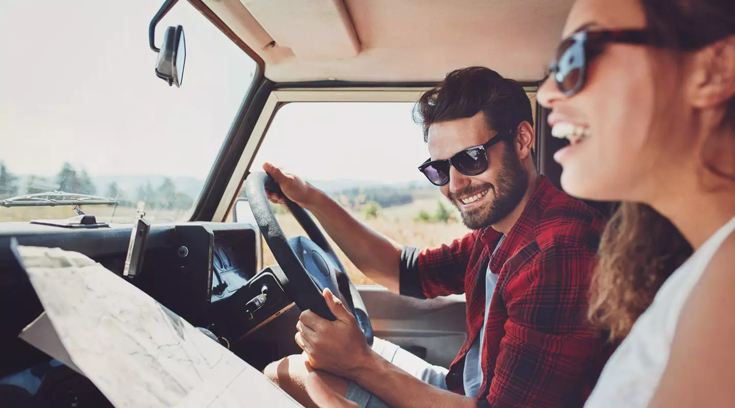 Couple in car driving looking at map