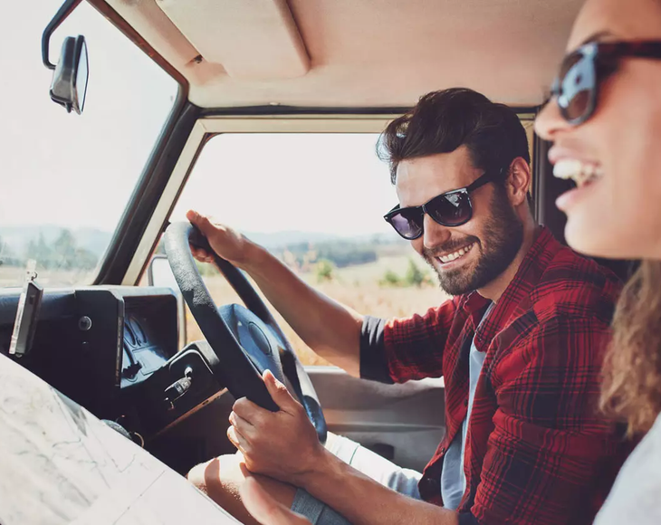 Couple in car driving looking at map