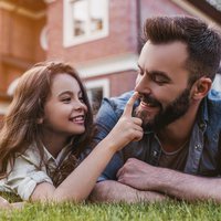 Father and daughter on grass in front of home