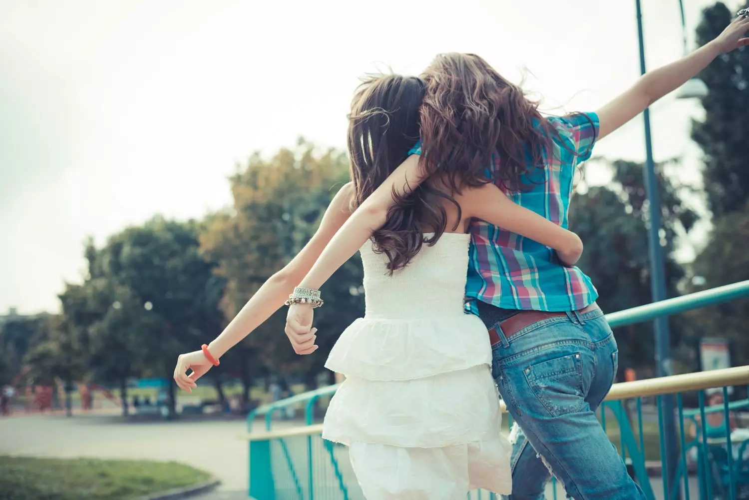 2 girls with their arms around each other facing away