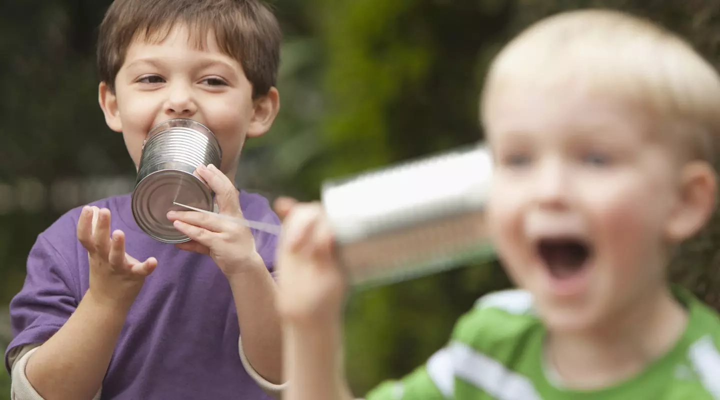 2 boys playing telephone with cans