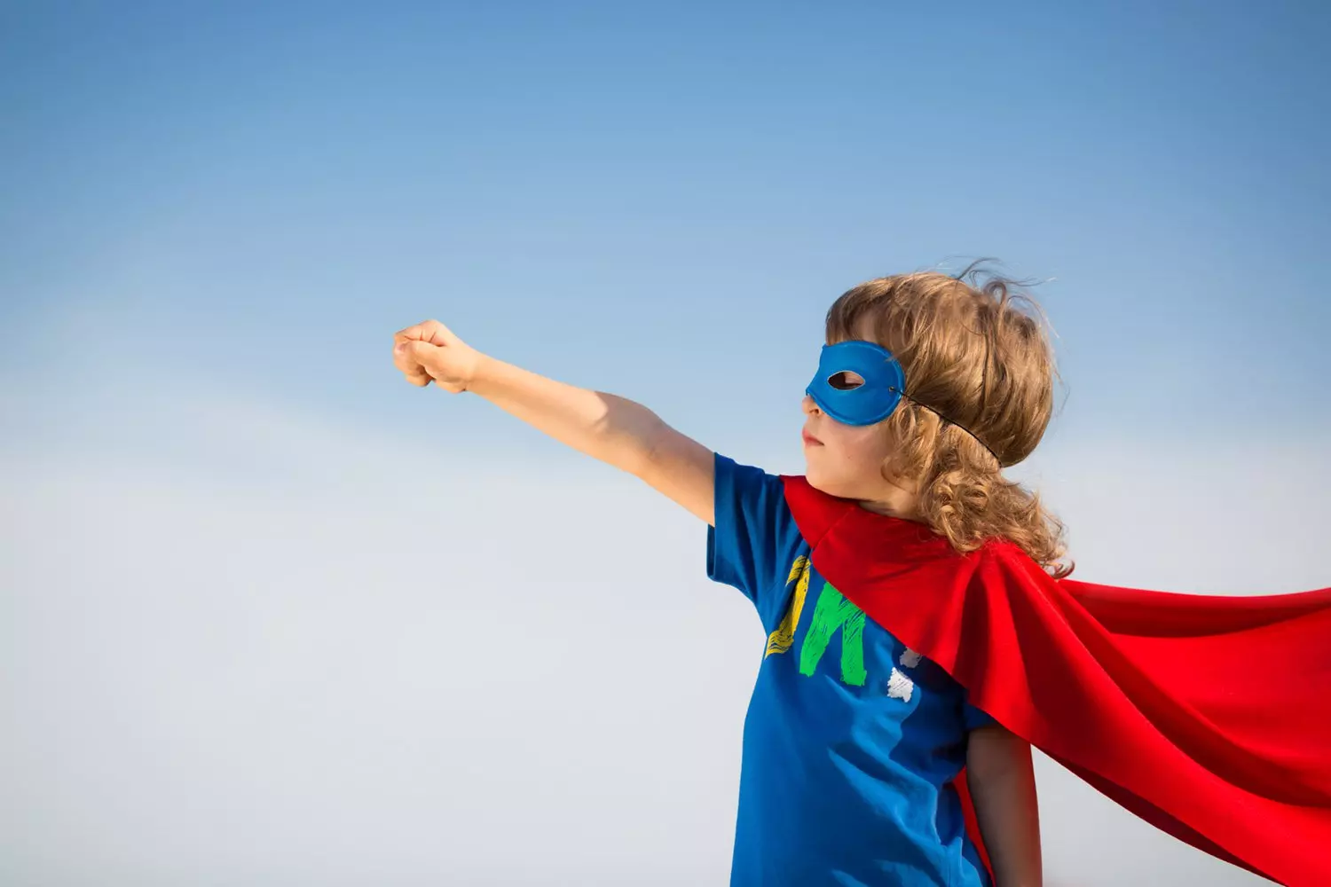 Young boy being a hero with a cape and mask