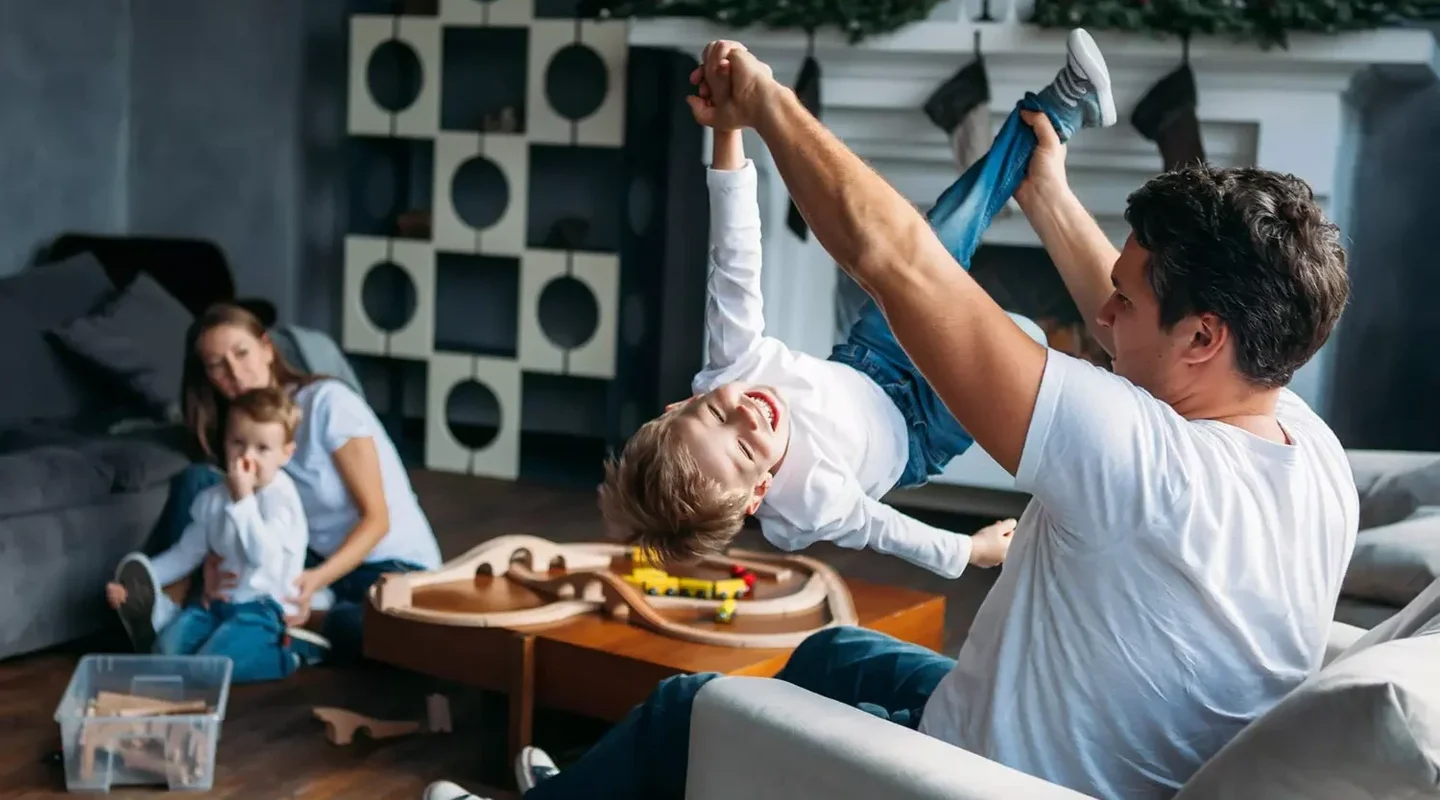 family playing in their living room - dad holding up son playfully