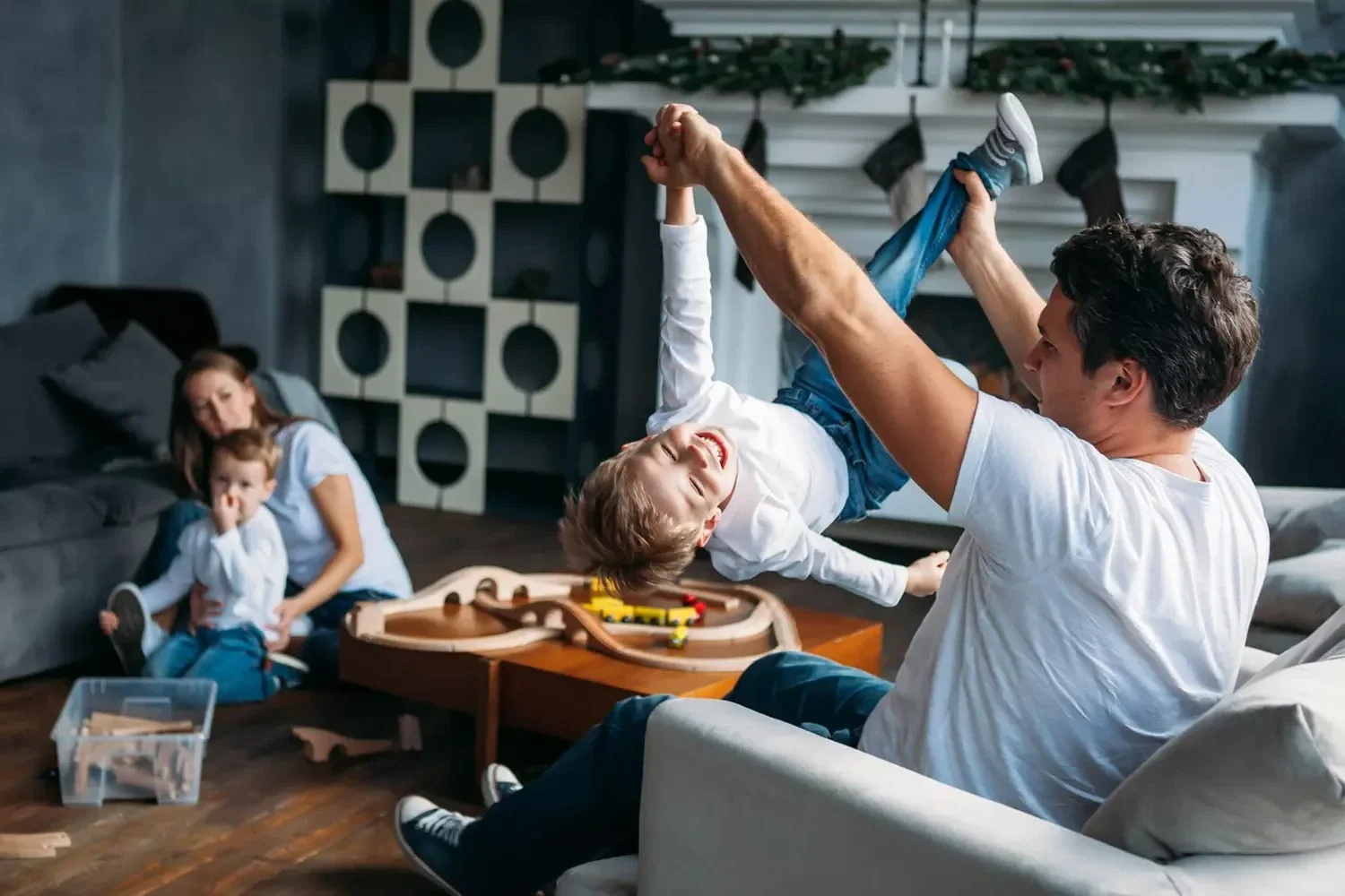 family playing in their living room - dad holding up son playfully