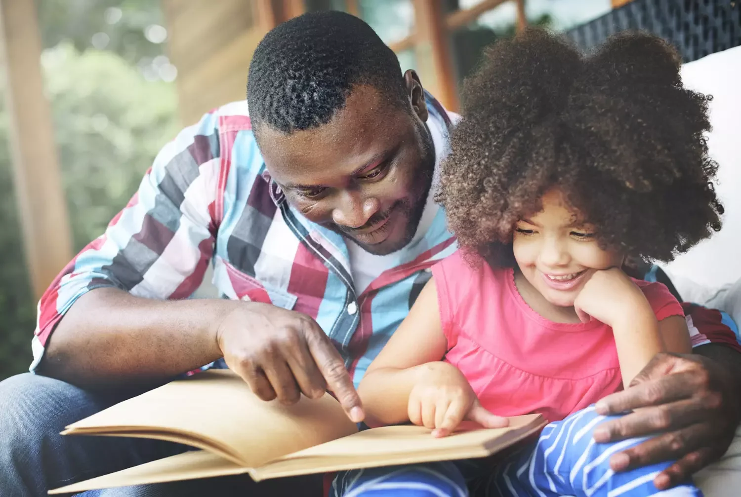 Father and daughter reading book on couch