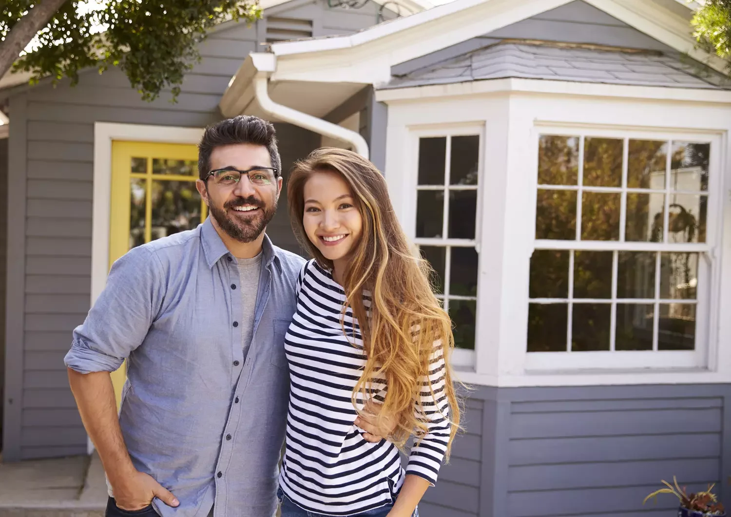 Happy couple standing in front of home