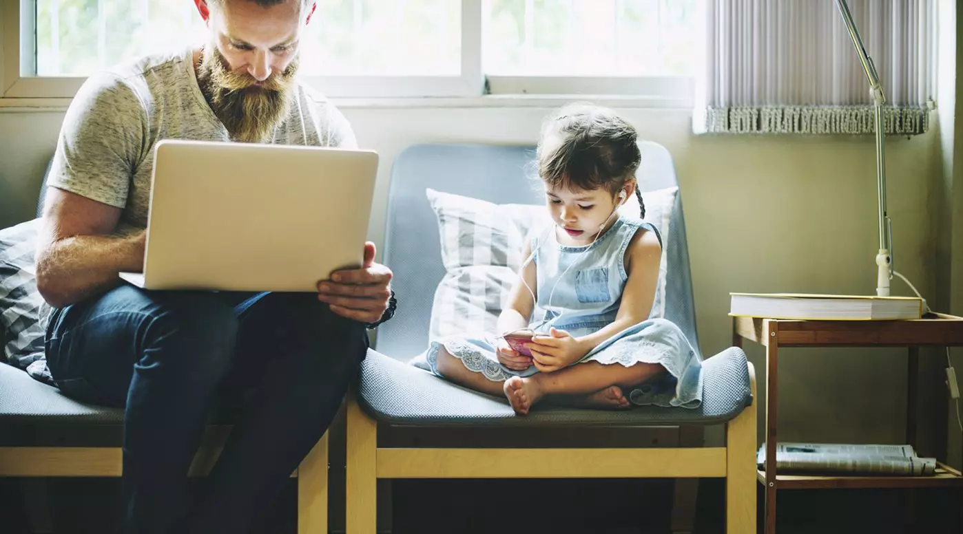 Man on computer with daughter listening to music