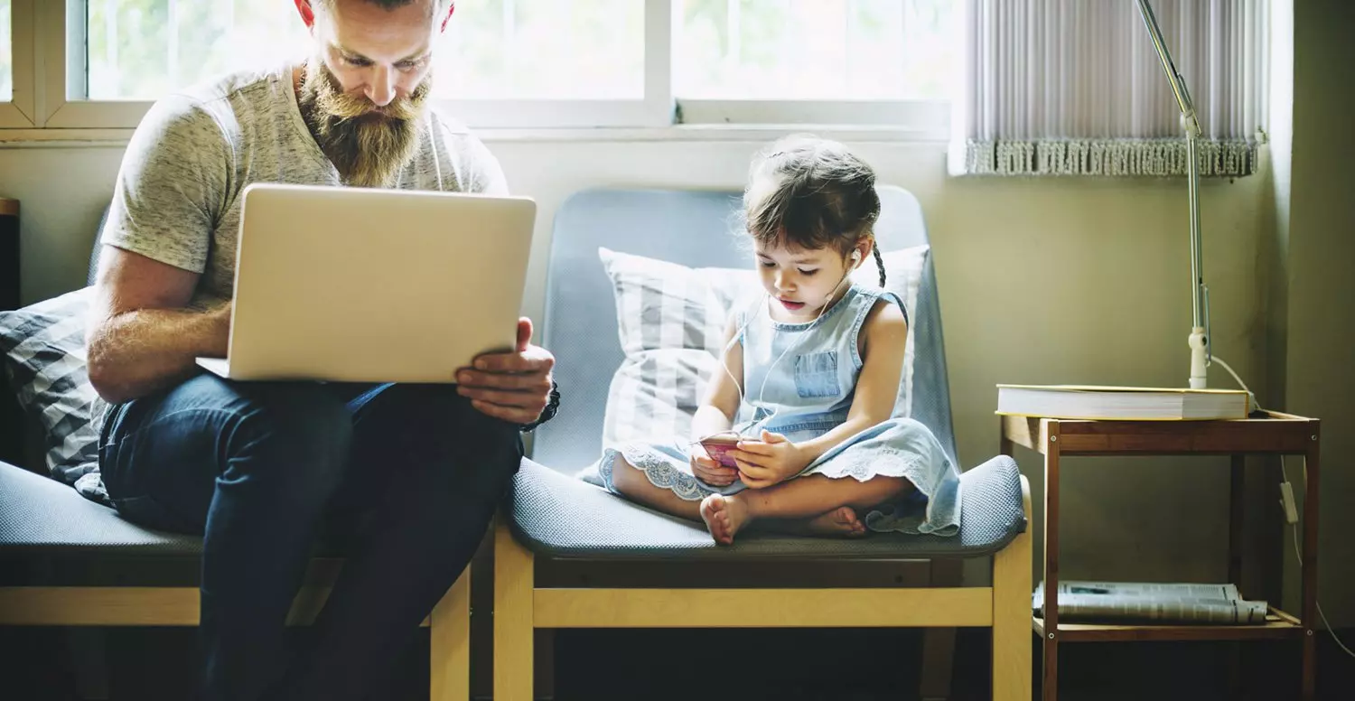 Man on computer with daughter listening to music