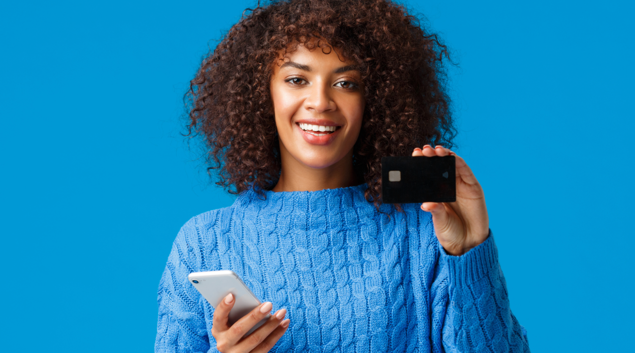 woman smiling and holding phone and debit card
