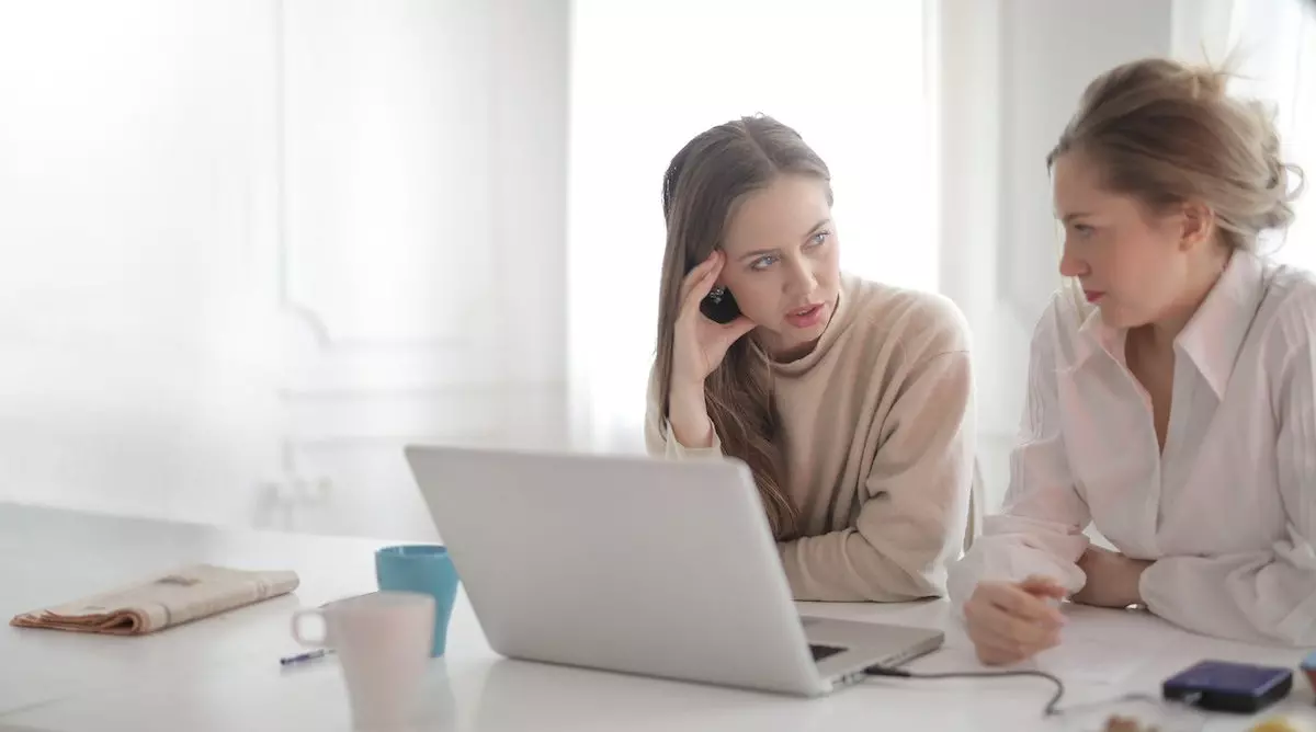 young women discussing at laptop