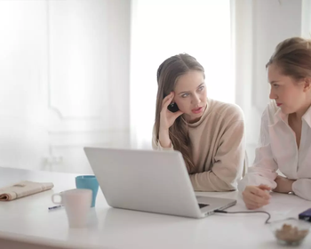young women discussing at laptop