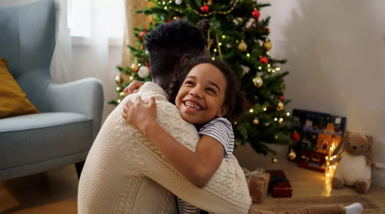 child hugging father in front of decorated tree