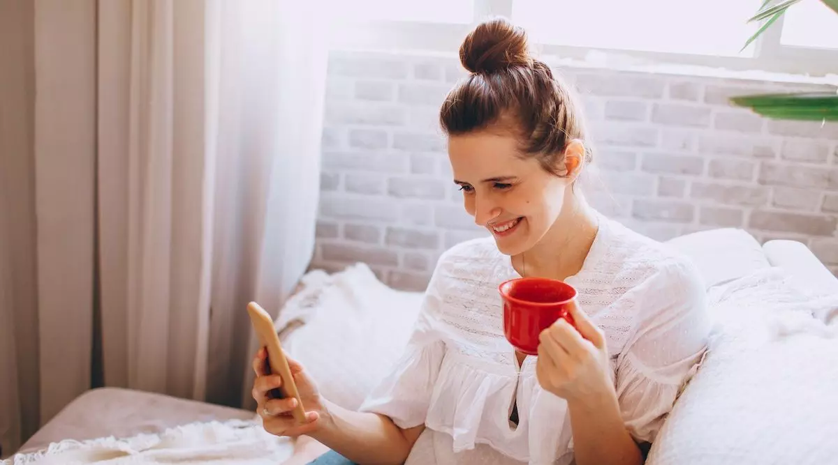woman with coffee mug looking at phone_mirror