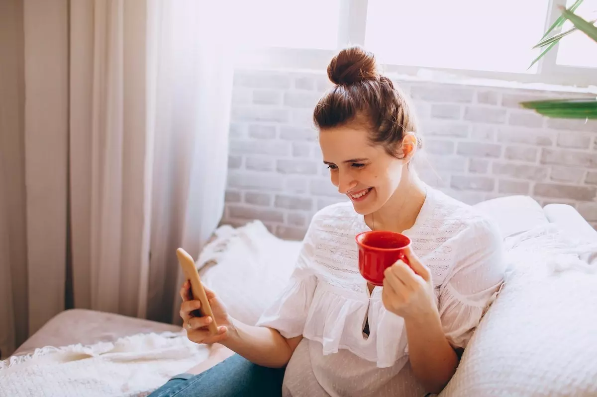woman with coffee mug looking at phone_mirror