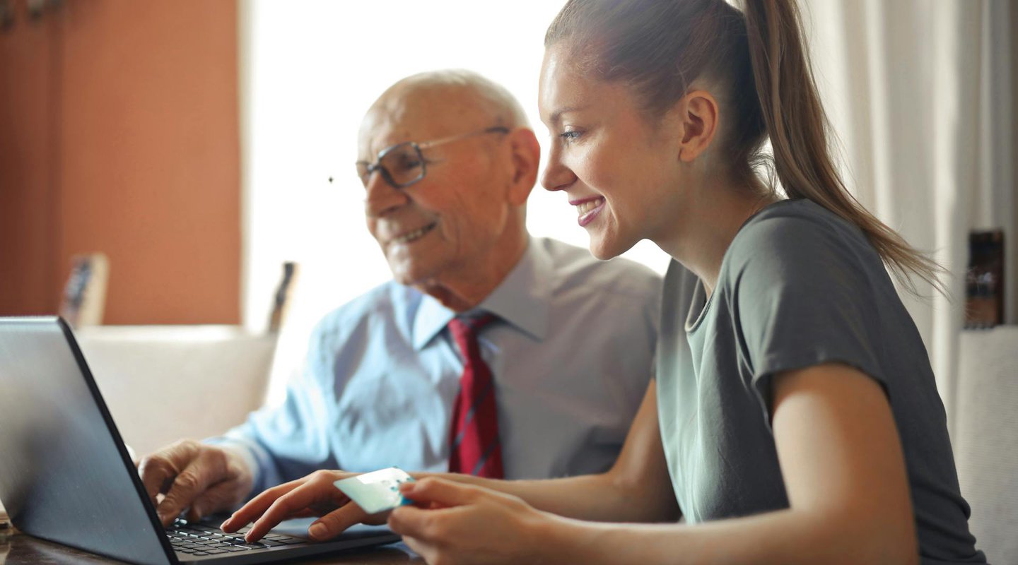 young woman and older man using laptop