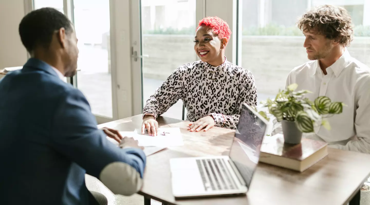 man and woman talking to advisor with laptop.webp